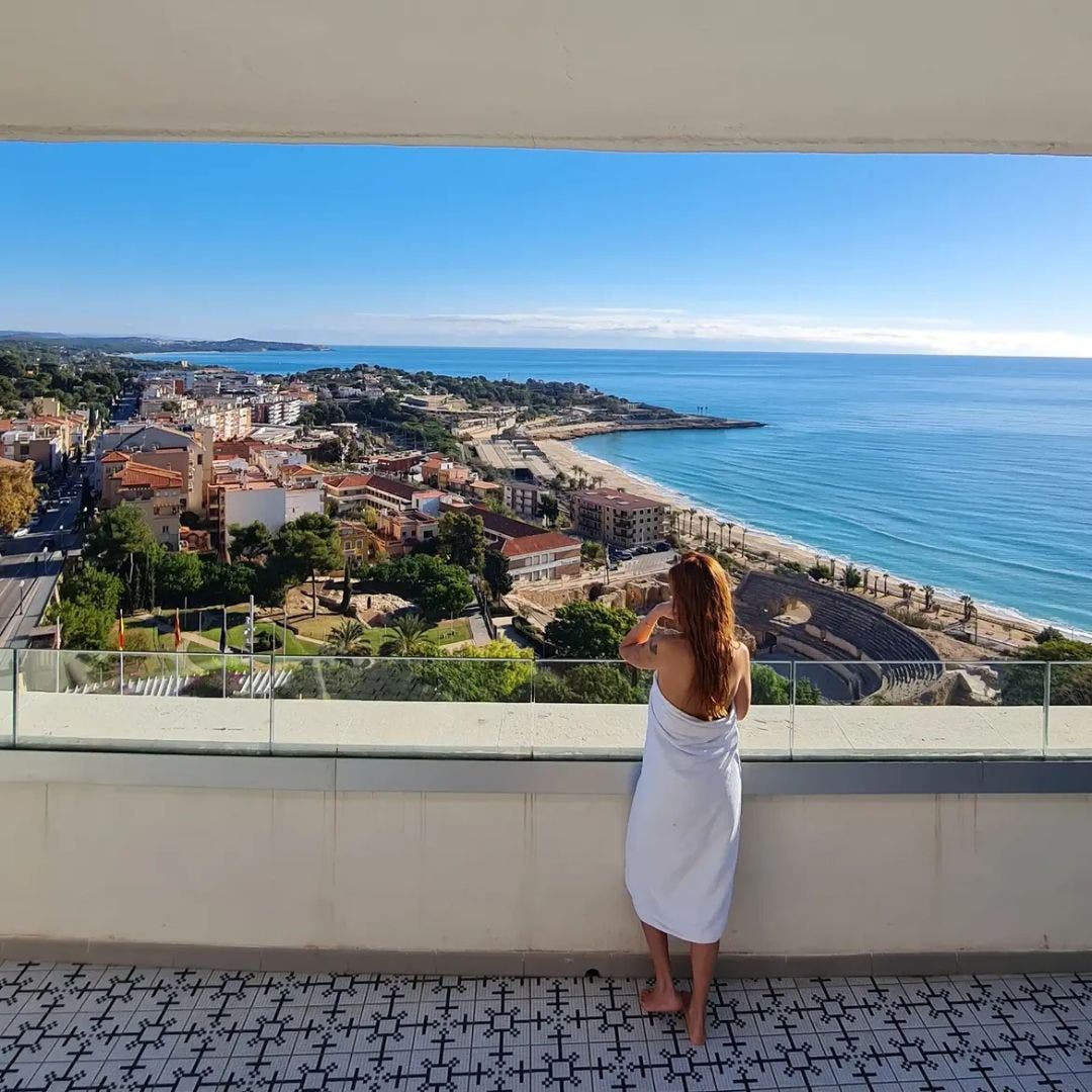 Mujer en toalla mirando las vistas desde su habitación de H10 Imperial Tarraco