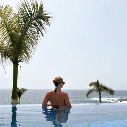 Young woman in the H10 Atlantic Sunset infinity pool looking out towards the beach.