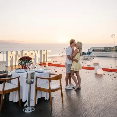 Couple standing in front of a "Marry Me" sign with the ocean in the background at H10 Atlantic Sunset.