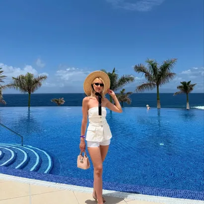 Woman in a straw hat with a swimming pool and the ocean in the background at H10 Atlantic Sunset Horizons Collection.