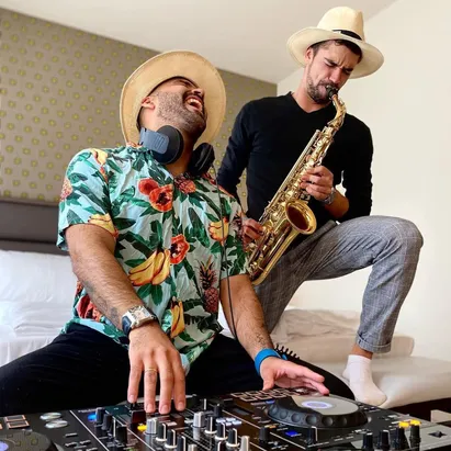 Musiker, die mit einem Saxophon und einem DJ-Controller in einem Zimmer des H10 Berlin Ku'Damm auftreten.
