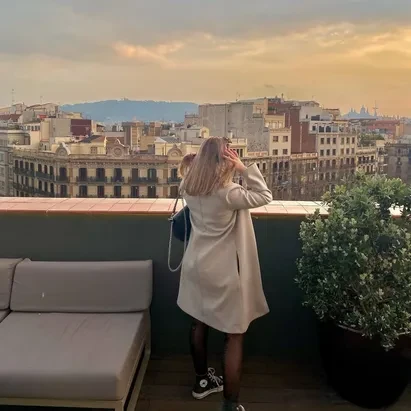 Mulher com roupa de inverno a assistir ao pôr do sol no terraço do H10 Casanova em Barcelona.