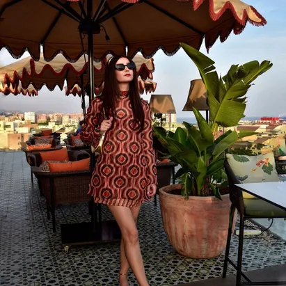 Donna sulla terrazza panoramica dell'H10 Croma Málaga con occhiali da sole neri e ombrelloni sullo sfondo.