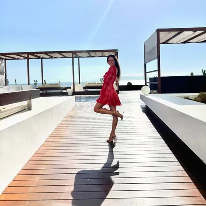 Woman in a pink dress and high-heeled sandals on the beach at H10 Gran Tinerfe.