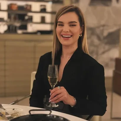 Blonde woman with a serving of black rice and a glass of cava in her hand.