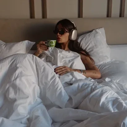 Mujer tomando café mientras disfruta de una mañana relajada en una habitación de H10 Puerta de Alcalá