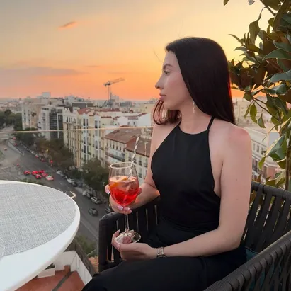 Mujer disfrutando de un cocktail con el sol de atardecer en la terraza del H10 Puerta de Alcalá