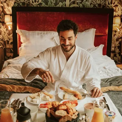 Man enjoying room service breakfast at The One Alma Paris, wearing the hotel bathrobe.