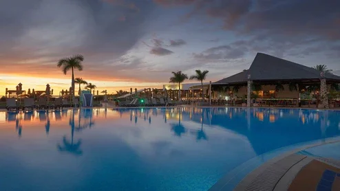 Blick auf das Hotel und den Pool bei Sonnenuntergang
