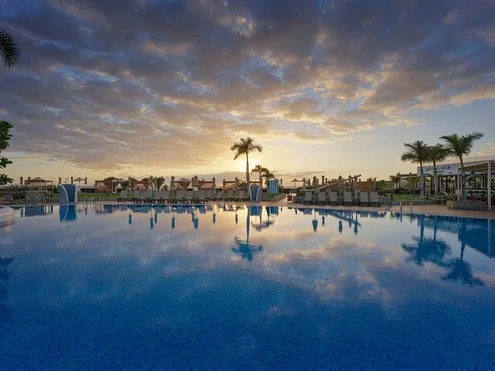Blick auf das Hotel und den Pool bei Sonnenuntergang
